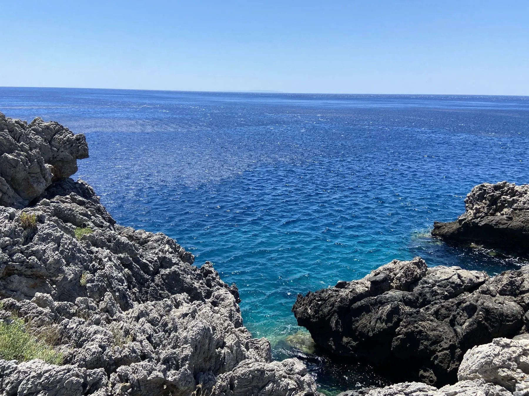 A rocky shoreline above deep blue and turquoise water